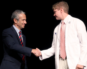 Dr. Giuseppe Gumina (left) welcomes a new P1 to the Presbyterian College School of Pharmacy at the 2024 White Coat Ceremony.